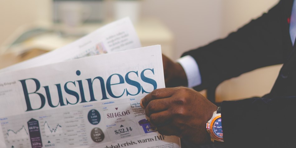 Man in suit reading the Business section of a newspaper
