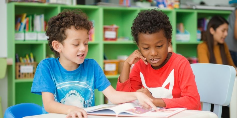 Two elementary students reading book in classroom