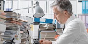 Man working at desk with piles of paperwork
